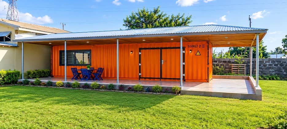 Orange snack shop with a covered veranda and blue chairs on a green lawn